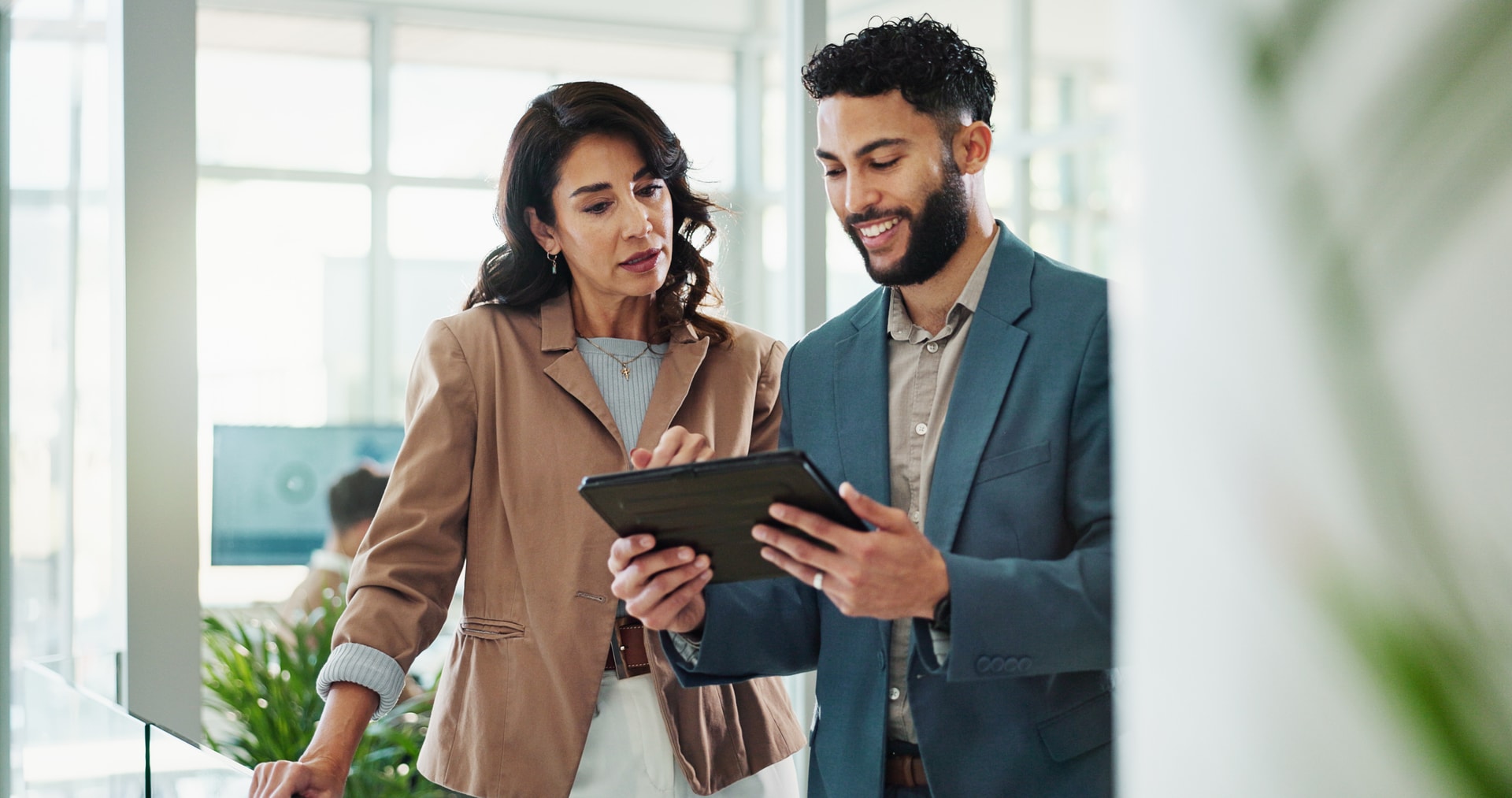 Indépendants & Commerces - Deux professionnels consultant une tablette dans un bureau moderne